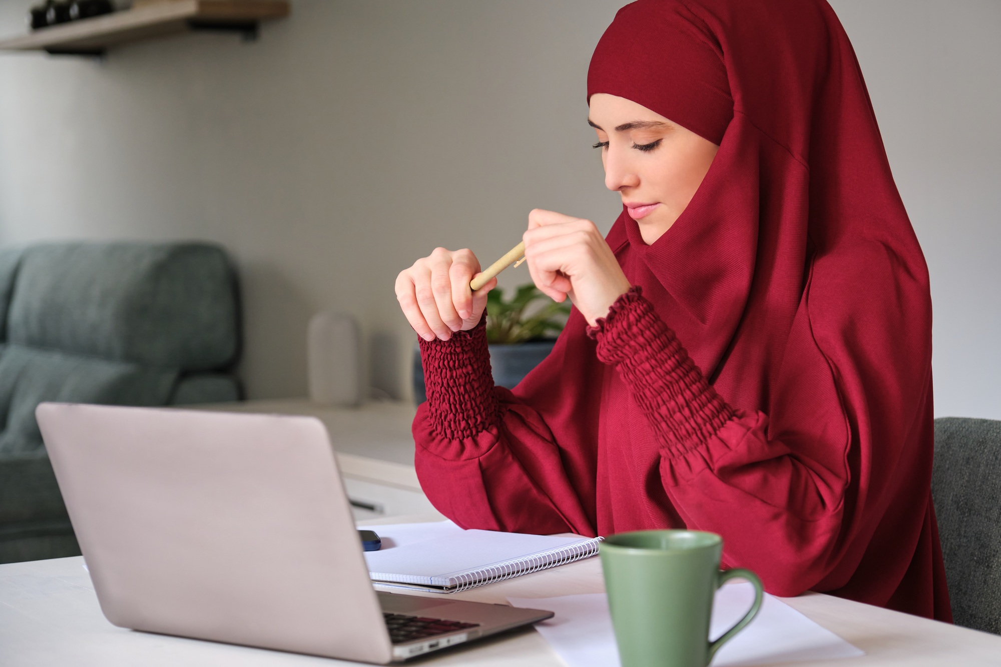 Maklon Minuman Promo Ramadhan 1 Muslim young woman in hijab using laptop at home.